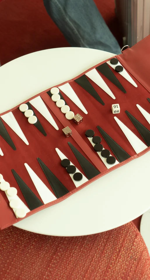 A backgammon board rolled out and mid-game, checkers stacked on the points with the dice and the doubling cube down on the leather